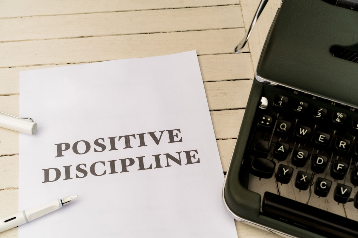 a piece of paper that says positive discipline next to a typewriter